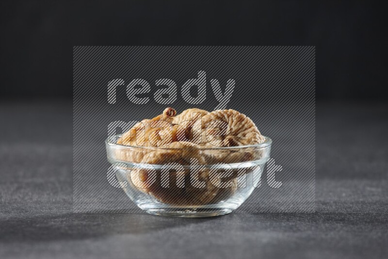 A glass bowl full of dried figs on a black background in different angles