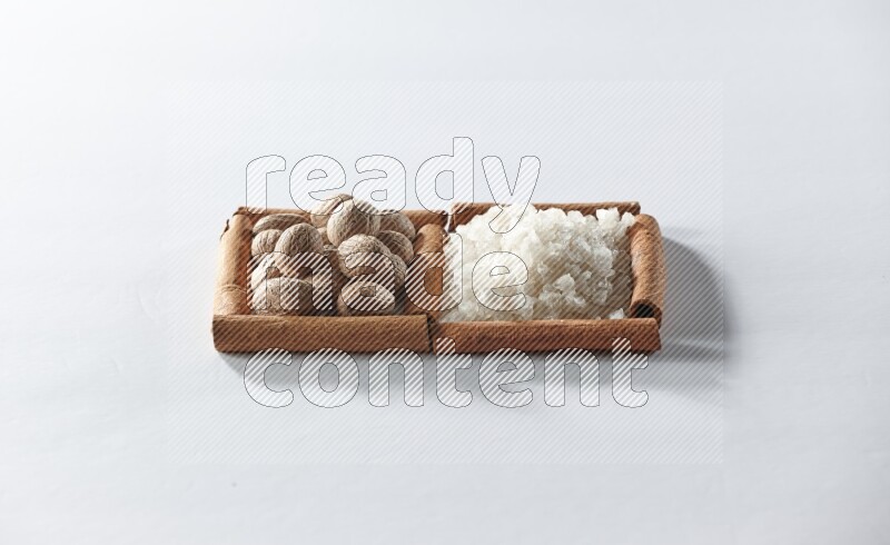 2 squares of cinnamon sticks full of white salt and nutmegs on white flooring