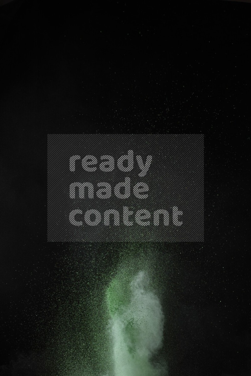 A side view of green powder explosion on black background