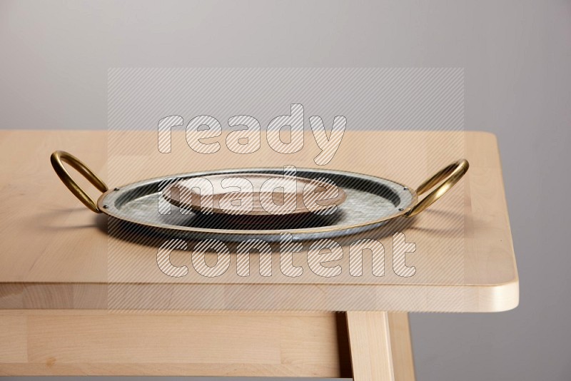 multicolored plate placed on a rounded stainless steel tray with golden handels on the edge of wooden table