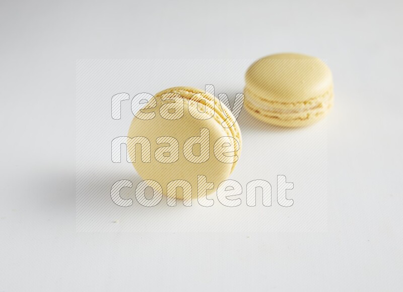 45º Shot of two Yellow Vanilla macarons on white background