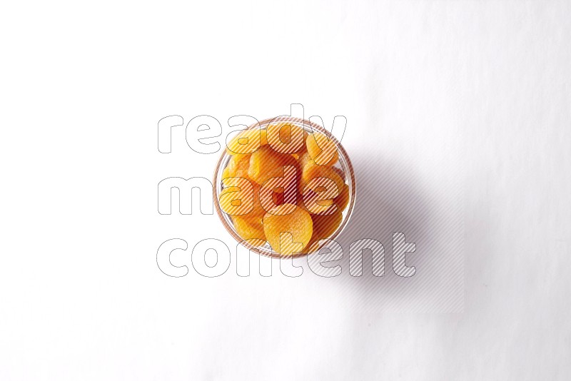 Dried apricots in a glass bowl on white background