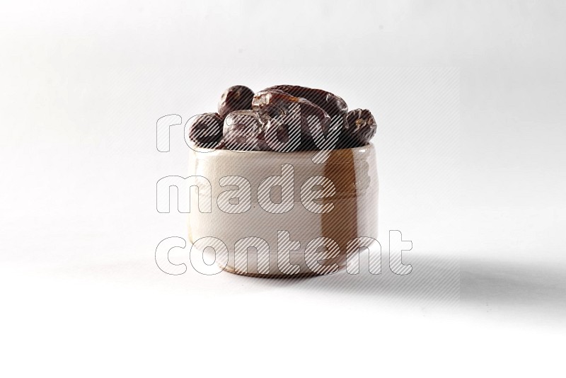 Dates in a beige pottery bowl on white background