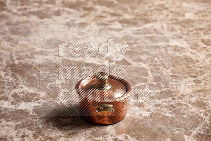 A small copper pot on beige marble background