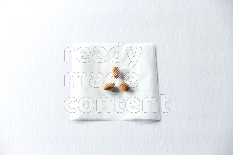 3 peeled almonds on a piece of paper on a white background in different angles