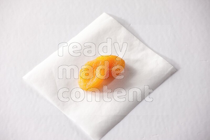 حبتان من المشمش المجفف على قطعة من الورق على خلفية بيضاء