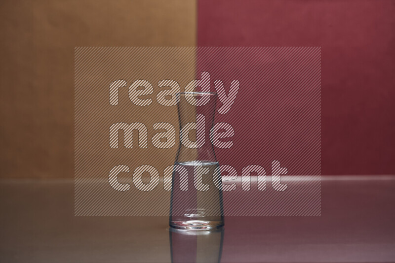 The image features a clear glassware filled with water, set against brown and dark red background