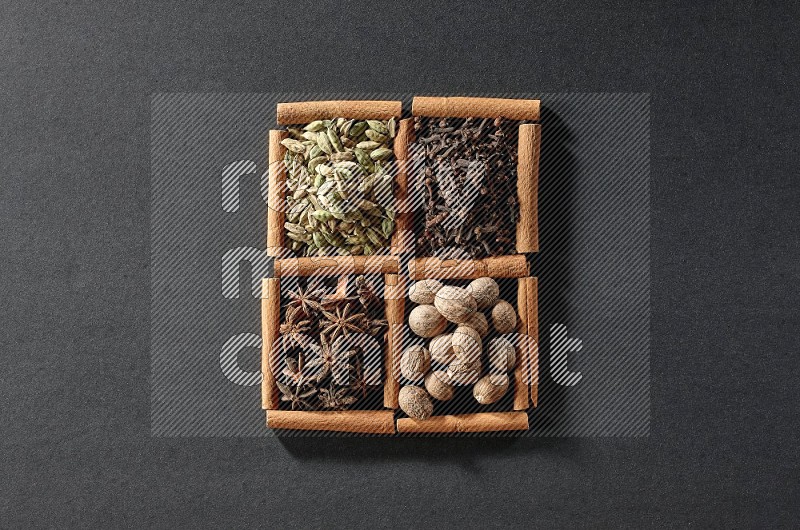 4 squares of cinnamon sticks full of cardamom, star anise, nutmegs and cloves on black flooring