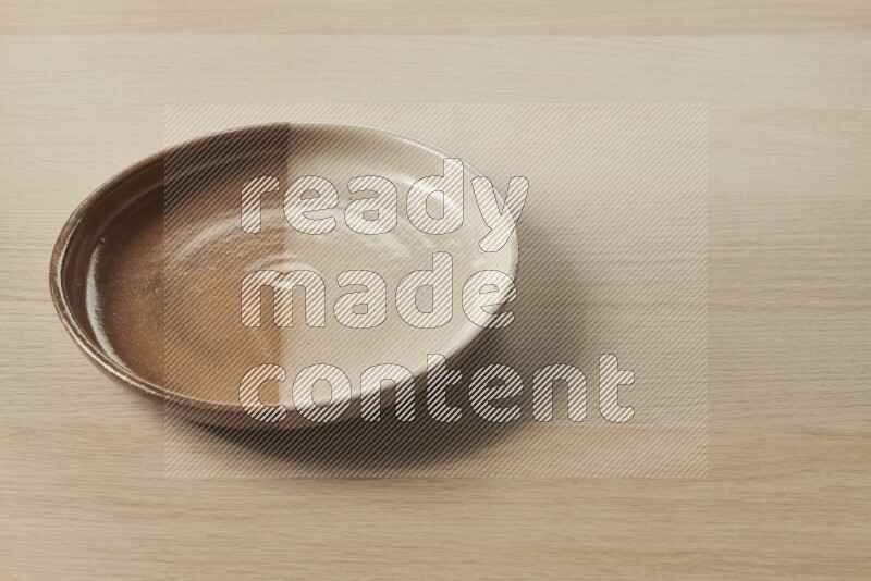 A multicolored pottery plate on light wooden background