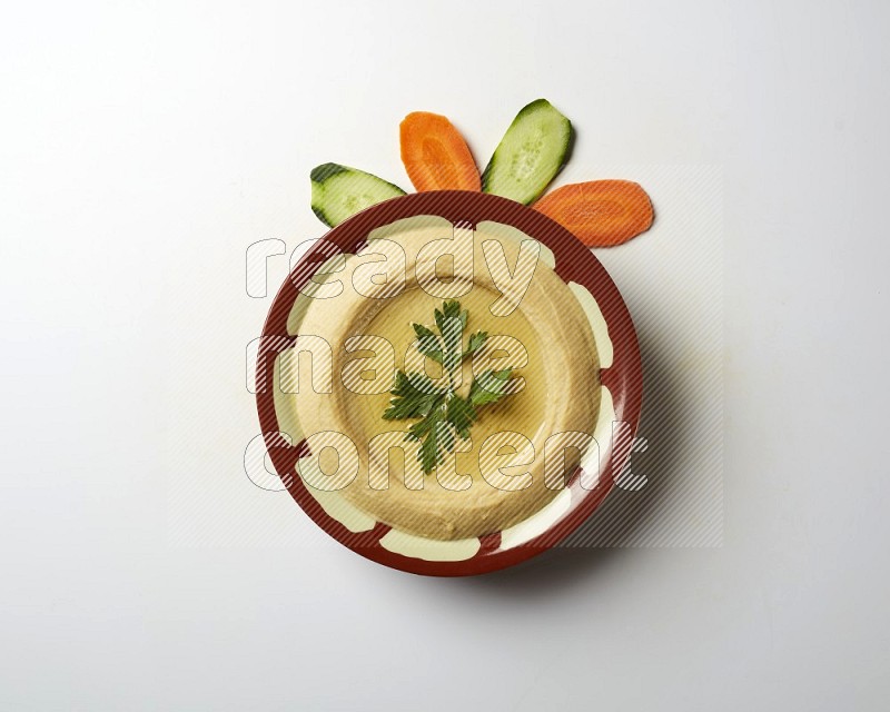 Hummus in a traditional plate garnished with parsley on a white background