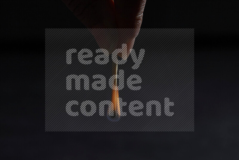 A burning matchstick isolated on dark backdrop