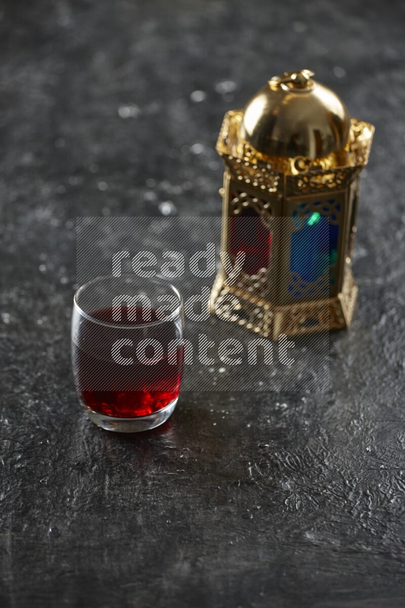 A golden lantern with different drinks, dates, nuts, prayer beads and quran on textured black background