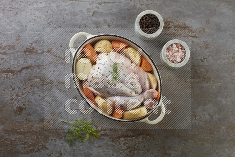 whole raw chicken on in a white ceramic pot direct on a rustic grey background