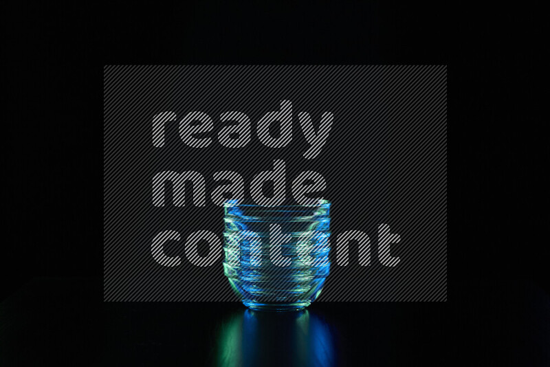 Glassware with rim light in blue and green against black background