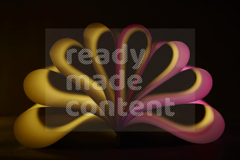 فن تجريدي يعرض منحنيات وتدرجات اللون الأصفر والوردي مكونه بضوء ملون