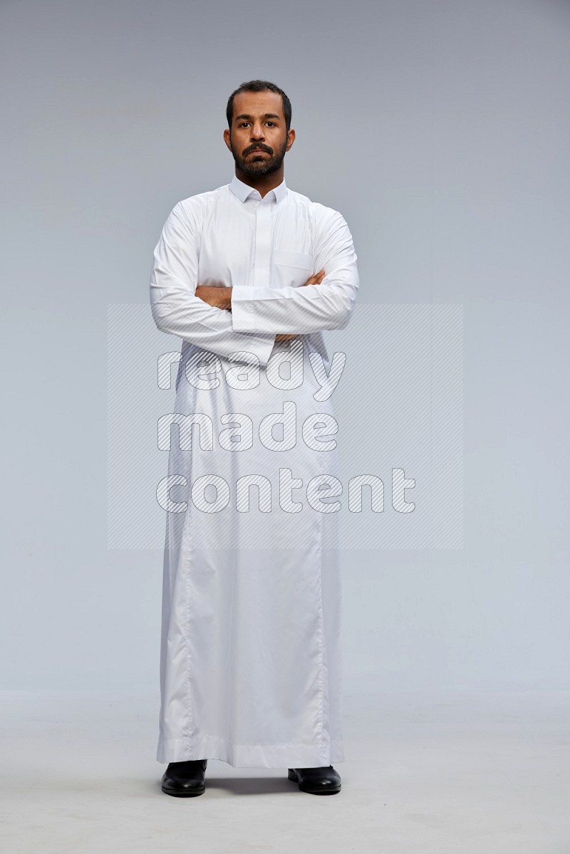 Saudi man wearing Thob standing with crossed arms on Gray background