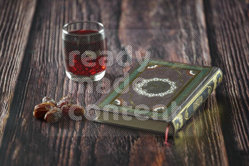 Quran with dates, prayer beads and different drinks all placed on wooden background