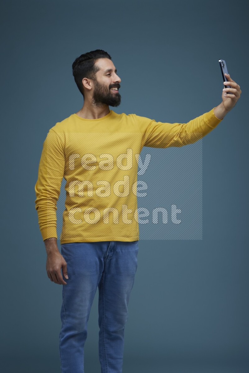 Man Taking a Selfie  in a blue background wearing a yellow shirt