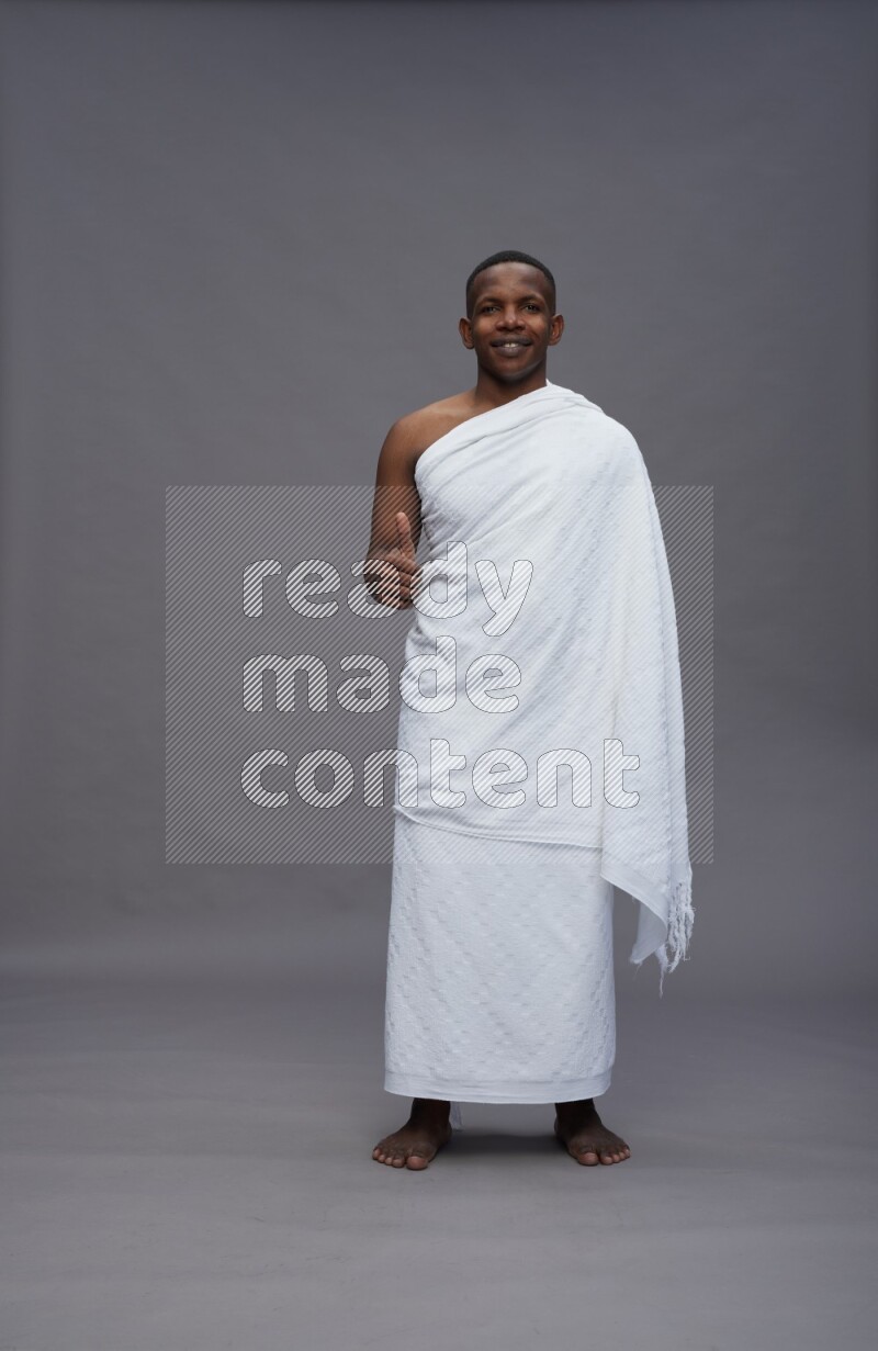 A man wearing Ehram Standing Interacting with the camera on gray background