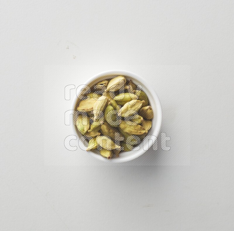 Top-view shot of Cardamon in a container on white background
