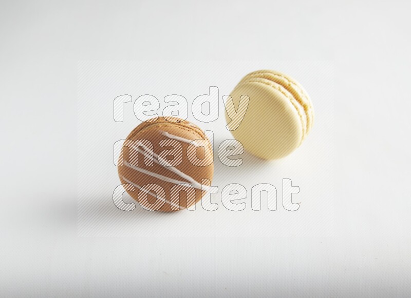 45º Shot of of two assorted Brown Irish Cream, and Yellow Vanilla macarons on white background