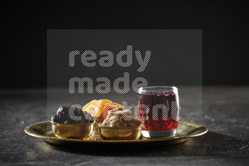 Dried fruits in metal bowls with Hibiscus on a tray in dark setup
