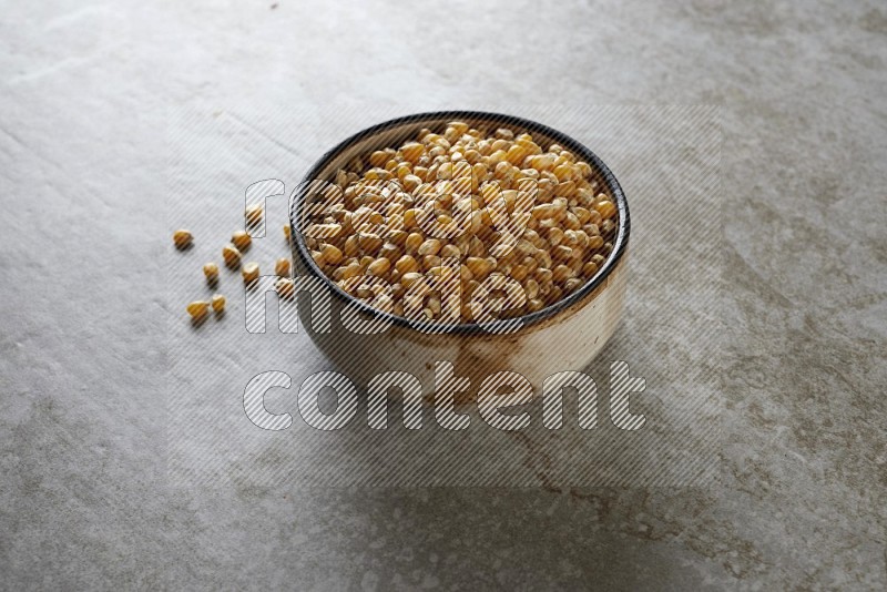 corn kernel in multi-colored pottery bowl on a grey textured countertop