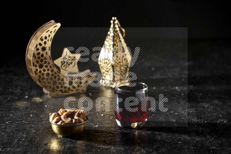 Nuts in a metal bowl with Hibiscus beside golden lanterns in a dark setup