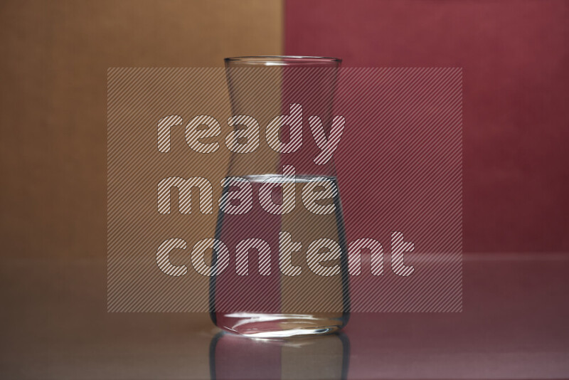 The image features a clear glassware filled with water, set against brown and dark red background