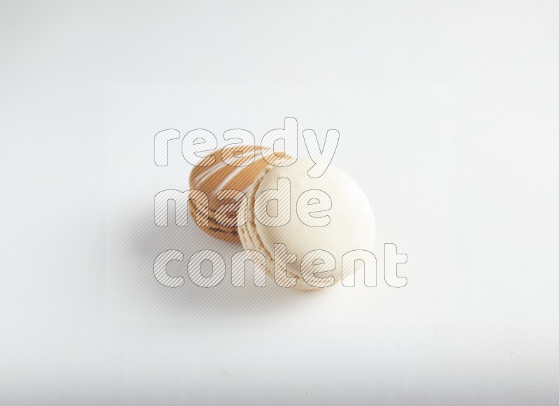45º Shot of of two assorted Brown Irish Cream, and White Caramel fleur de sel macarons on white background