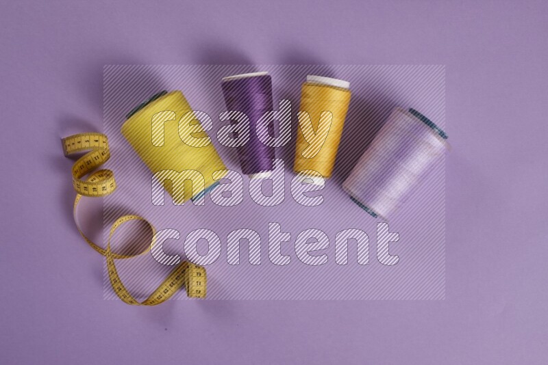 A yellow and purple collection of sewing and tailoring tools arranged on a purple background