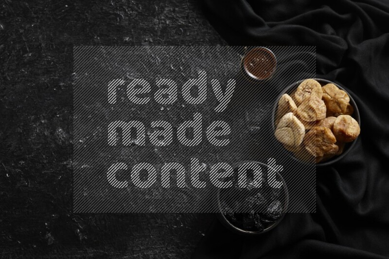 فواكه مجففة في أطباق فخارية مع القهوة علي خلفية سوداء خشبية