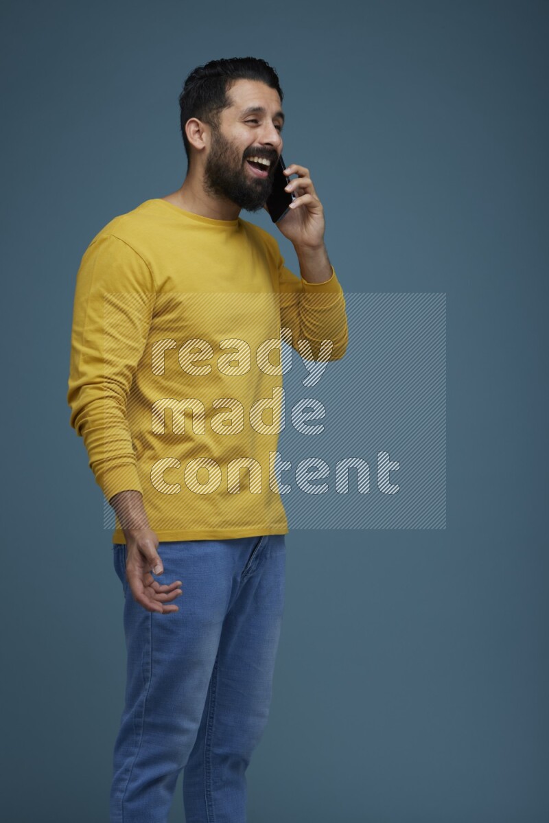 A man having a calling in a blue background wearing a yellow shirt