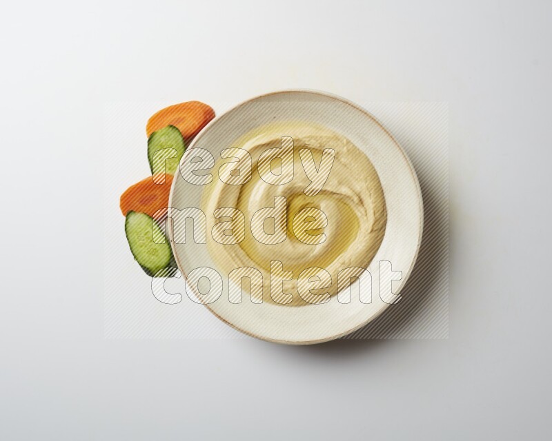 Hummus in a pottry plate garnished with olive oil on a white background