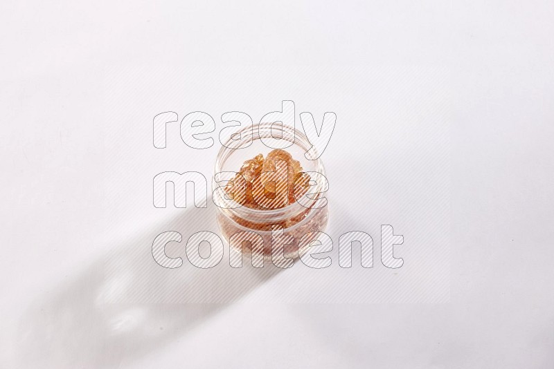 A glass jar filled with gum arabic on white flooring in different angles