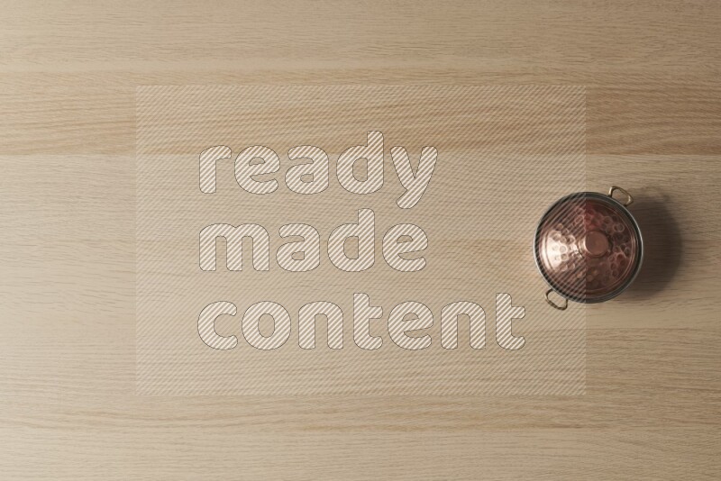 وعاء نحاسي صغير على خلفية خشبية فاتحة