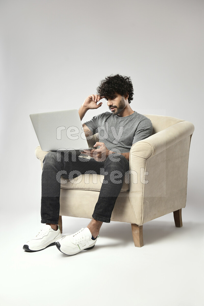 A man wearing casual sitting on a chair working on a laptop on white background