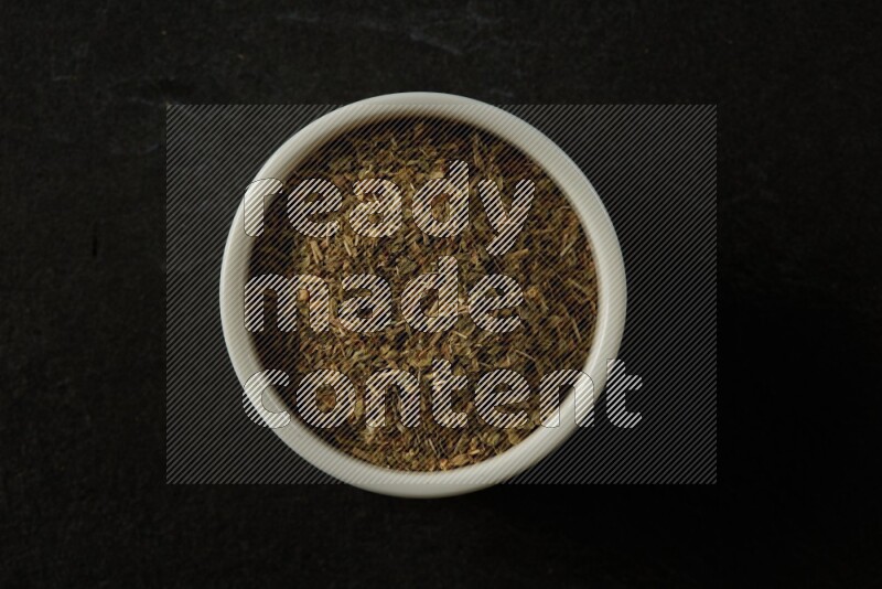 wooden round sauce bowl filled with herbs on grey textured countertop