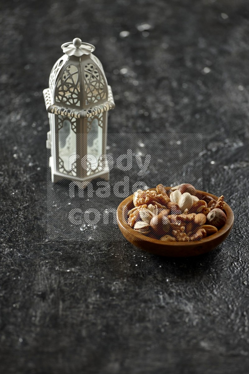 A white lantern with drinks, dates, nuts, prayer beads and quran on textured black background