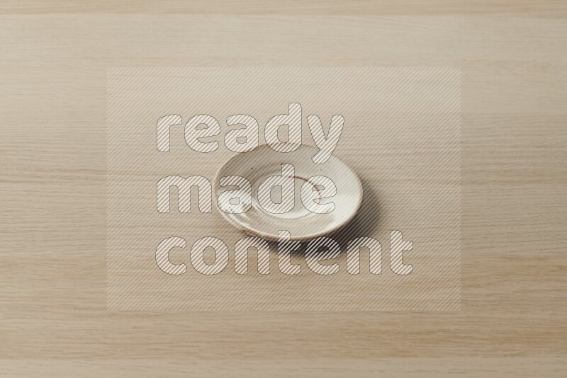 A pottery coaster on light wooden background
