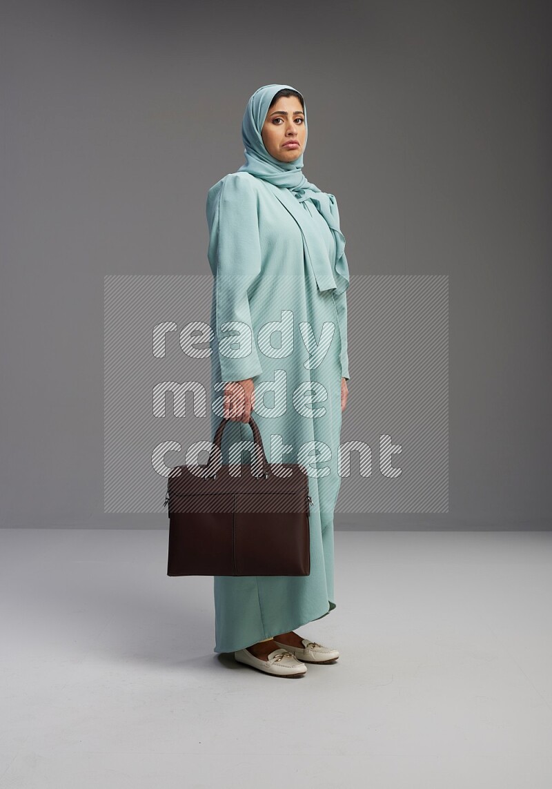 Saudi Woman wearing Abaya standing holding bag on Gray background