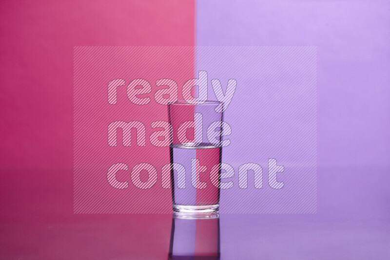 The image features a clear glassware filled with water, set against pink and light purple background