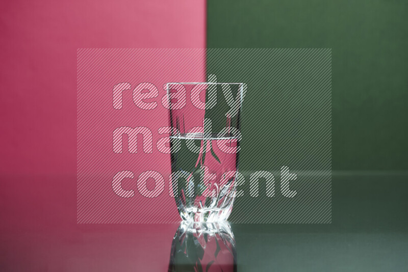 The image features a clear glassware filled with water, set against pink and dark green background