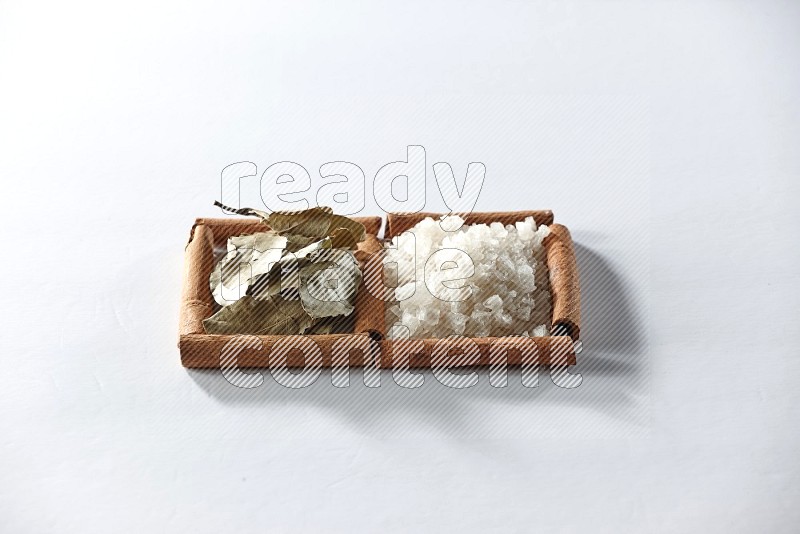 2 squares of cinnamon sticks full of white salt and laurel bay leaves on white flooring