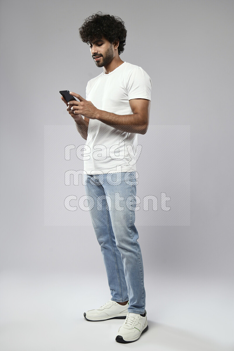 A man wearing casual standing and texting on the phone on white background