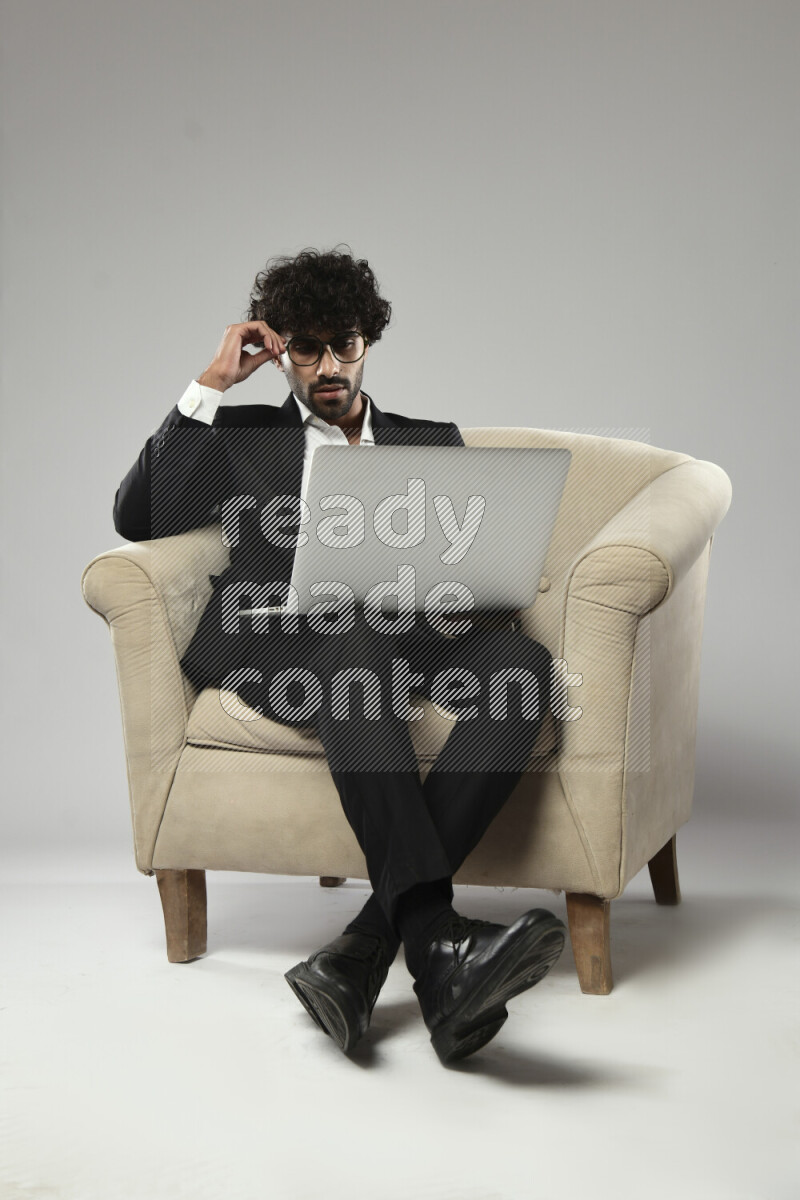 A man wearing formal sitting on a chair working on a laptop on white background