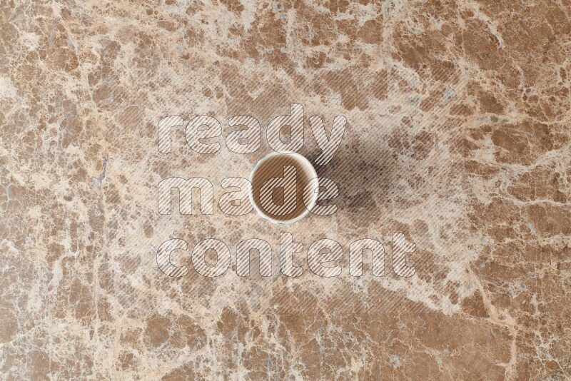A pottery cup on beige marble background