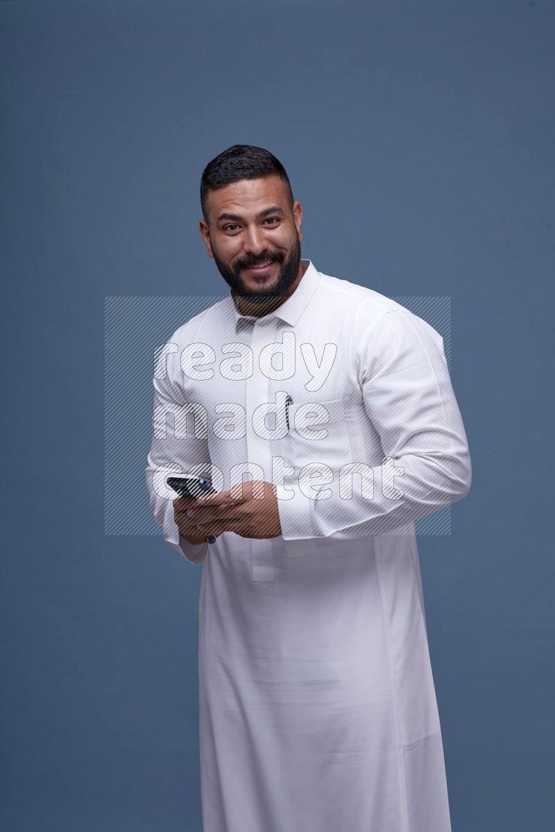 رجل سعودي يرتدي ثوب ابيض ويستخدم جواله
