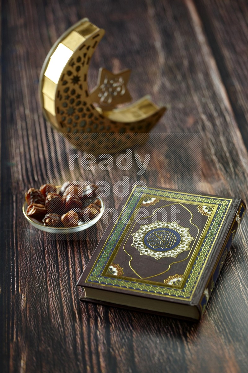 A crescent lantern with drinks, dates, nuts, prayer beads and quran on brown wooden background