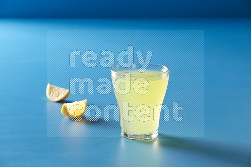 glass of lemon juice on blue background